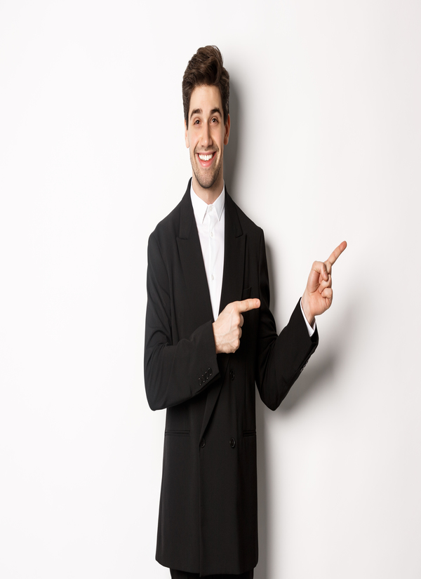 A handsome man in a New Year party outfit, smiling and pointing his fingers to the right, showcasing an advertisement. White background.